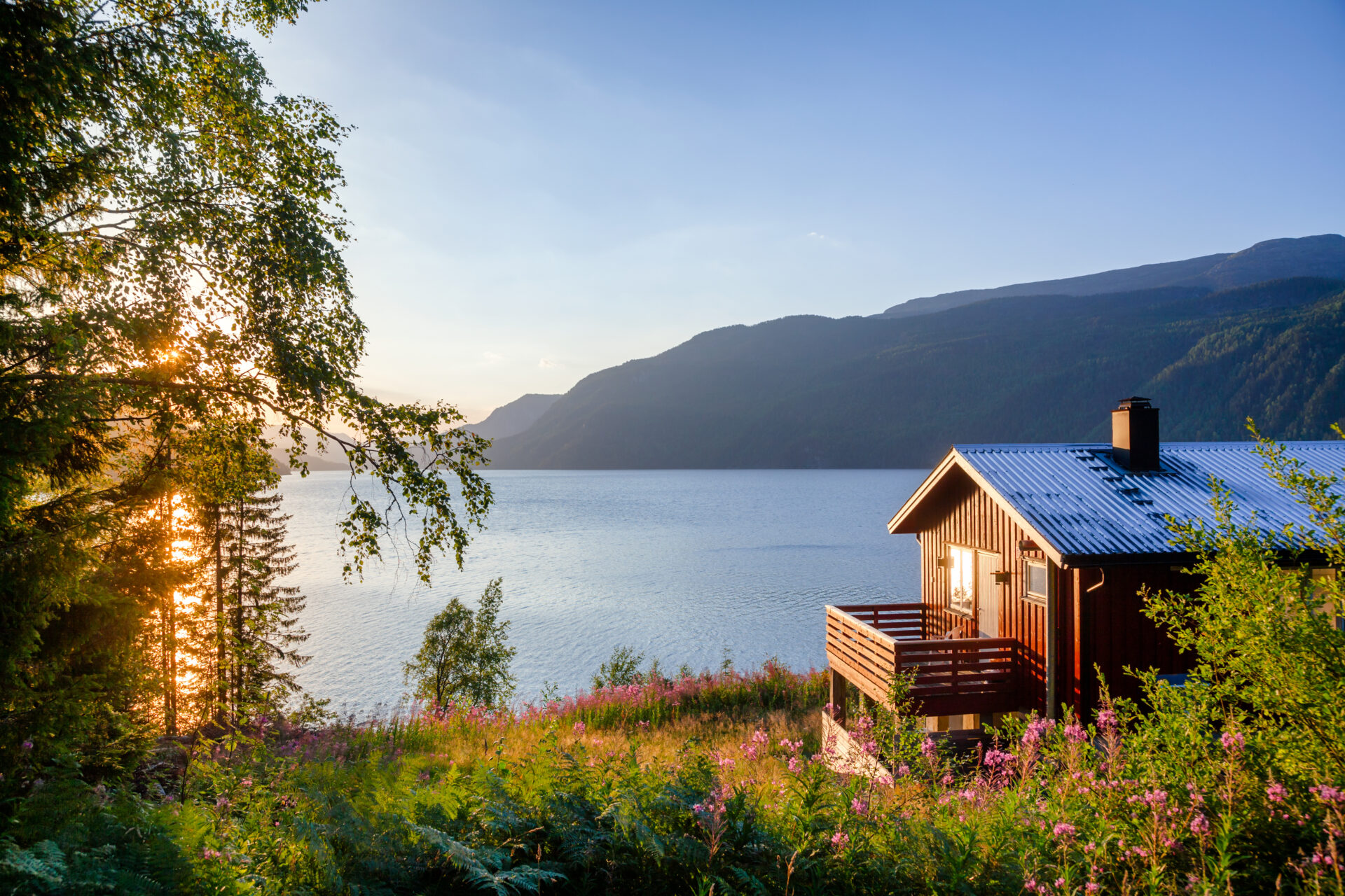Norwegian wooden summer house (Hytte) with terrace overlooking scenic lake at sunset, Telemark, Norway, Scandinavia